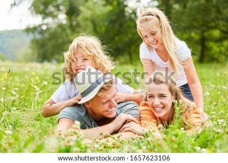 Family and children are laughing and lying in the grass in the garden in spring