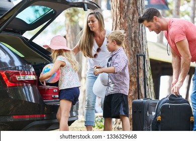 Family And Children Load Car With Luggage Before Traveling On Summer Vacation