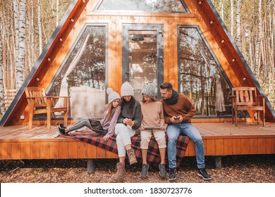 Family With Children On The Terrace Of Their House On An Autumn Day, Each With Their Own Gadget