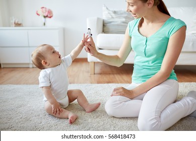 family, children and parenthood concept - happy smiling young mother and baby playing with finger puppet at home