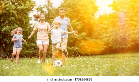 Family And Children Play Soccer Together In The Garden In Summer