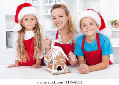 Family At Christmas Making A Gingerbread Cookie House Together