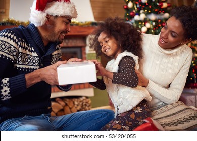 Family In Christmas Morning Opening Present Together
