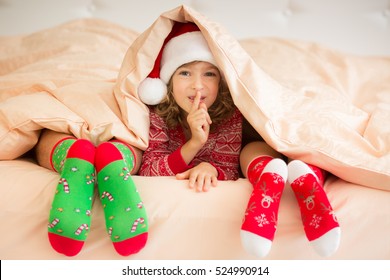 Family In Christmas Socks Lying On Bed. Mother, Father And Child Having Fun Together. People Relaxing At Home. Winter Holiday Xmas And New Year Concept