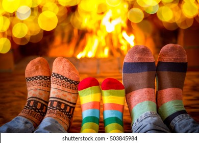 Family in Christmas socks near fireplace. Mother; father and baby having fun together. People relaxing at home. Winter holiday Xmas and New Year concept