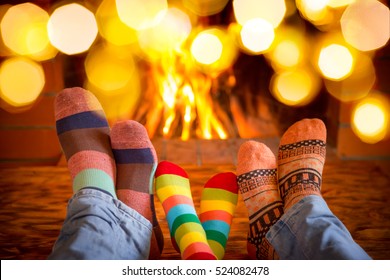 Family In Christmas Socks Near Fireplace. Mother; Father And Baby Having Fun Together. People Relaxing At Home. Winter Holiday Xmas And New Year Concept