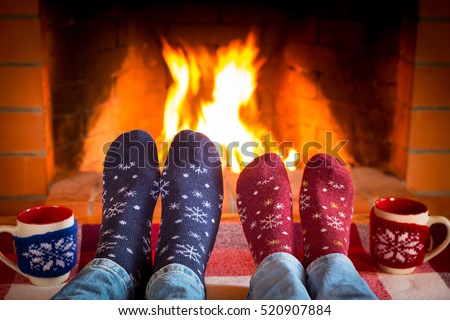 Family in Christmas socks near fireplace. Mother; father and baby having fun together. People relaxing at home. Winter holiday Valentine Day concept