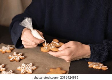 Family Christmas tradition at home. Boy decorating gingerbread cookie with sugar glaze from piping bag. Winter holiday celebration with child. - Shutterstock ID 2396424995