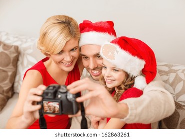Family, Christmas, X-mas, Winter, Happiness And People Concept - Smiling Family In Santa Helper Hats Taking Picture With Photo Camera