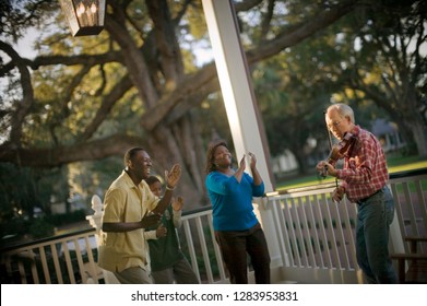 Family clapping while a musician plays a violin on their porch. - Powered by Shutterstock