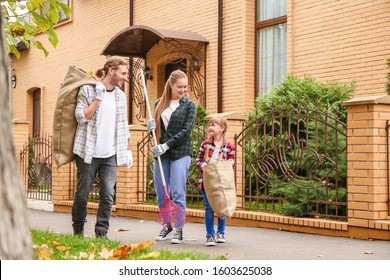 Family Cleaning Up Autumn Leaves Outdoors