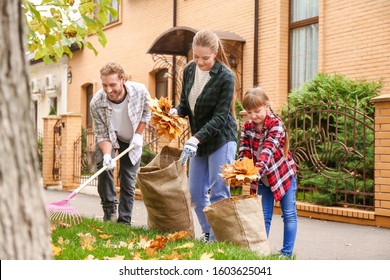 Family Cleaning Up Autumn Leaves Outdoors