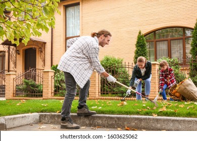 Family Cleaning Up Autumn Leaves Outdoors