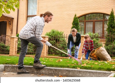 Family Cleaning Up Autumn Leaves Outdoors