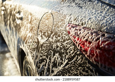 Family Cleaning Car In Self-service At Car Wash During Sunset. Car Covered In White Foam. Concept Of Easy And Fun Self-service