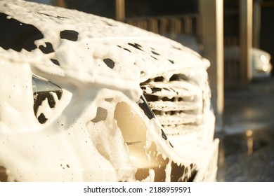 Family Cleaning Car In Self-service At Car Wash During Sunset. Car Covered In White Foam. Concept Of Easy And Fun Self-service