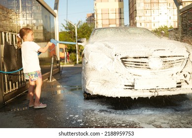 Family Cleaning Car In Self-service At Car Wash During Sunset. Car Covered In White Foam. Concept Of Easy And Fun Self-service