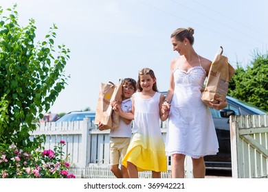 Family Coming Home From Shopping Groceries Carrying Bags