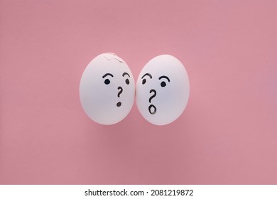 Family Concept, No People. Two Eggs With Painted Emotions, On A Pink Background. One Has A Surprised Expression, The Other Is Frightened. Something Went Wrong, One Egg Cracked. 