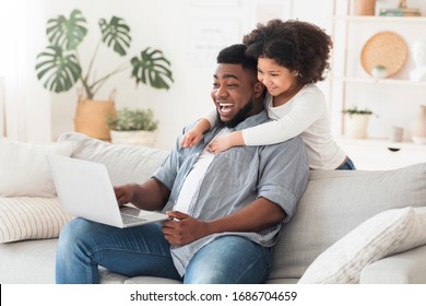 Family Conference. Black father and little daughter using laptop at home, making video call to grandparents, relaxing in living room