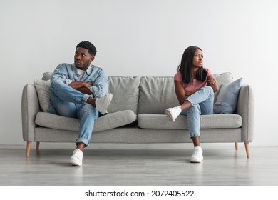 Family Conflict Concept. Stubborn black couple sit on couch back to back avoid talking after fight, offended man and woman separated on sofa ignoring one another, husband and wife not looking in eyes
