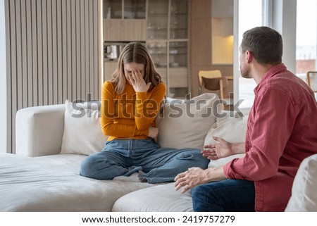 Family conflict misunderstanding between spouses. Man screaming shouting gesturing hands. Toxic relationship, manipulation. Woman cry discussing with cruel man in abusive relations sits on couch.  Stock photo © 