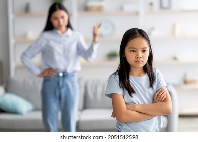 Family conflict. Mother and daughter quarreling at home, sulky child girl ignoring her mom, standing back to her with crossed arms, selective focus, copy space