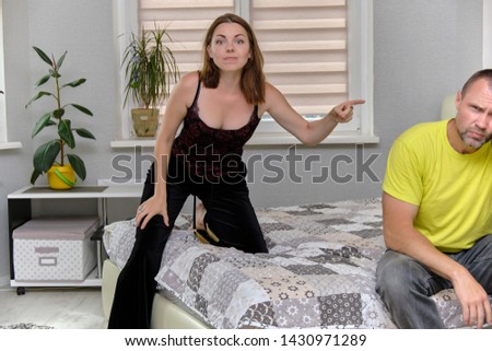 Family conflict, problems, family relations husband and wife at home in the bedroom. They are dissatisfied and irritated sitting on the bed, talking, arguing, proving something to each other.