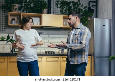 Family conflict. Young family. A pregnant woman and a man quarrel at home, shouting. They stand at home in the kitchen - Powered by Shutterstock