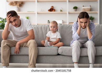 Family Conflicts. Cute infant baby sitting between offended parents after quarrel at home, young spouses with child suffering marital crisis, feeling depressed and frustrated, free space - Powered by Shutterstock