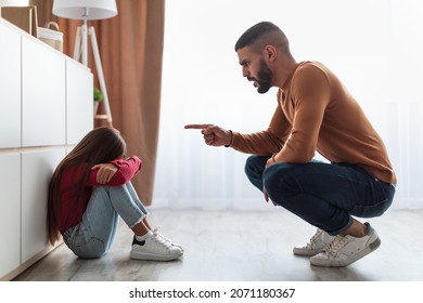 Family Conflicts And Punishment Concept. Profile Of Angry Annoyed Father Scolding His Upset Crying Little Daughter For Her Behaviour While She Sitting On The Floor At Home. Naughty Kid, Children Abuse - Powered by Shutterstock