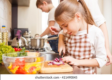 Family cooking background. Happy teen girl cutting onion on chopping board. 
