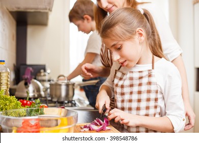 Family Cooking Background. Mum And Daughter Cutting Onion For Salad In The Kitchen