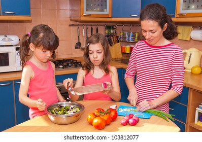 Family Cooking At Home. Happy Smiling Mother With Kids Cook Healthy Food Together At Kitchen. Family Preparing Salad