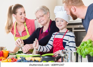 Family Cooking In Multigenerational Household With Son, Mother, Father And Grandfather