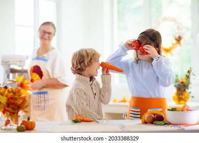 Family Cooking Thanksgiving Dinner. Grandmother And Child Cut Pumpkin In Decorated Kitchen. Mother And Kid Cook Vegetable Meal In Autumn. Grandparents Visit. Fall Season Food.