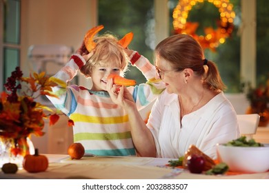 Family Cooking Thanksgiving Dinner. Mother And Child Cut Pumpkin In Decorated Kitchen. Mom And Kid Cook Vegetable Meal In Autumn. Cozy Indoor Evening In Dining Room. Fall Season Food.