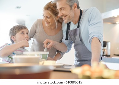 Family Cooking Together In Modern Home Kitchen