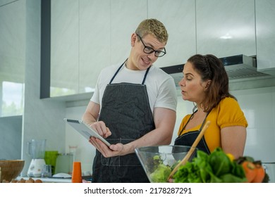 Family Cooking,Happy Family In The Kitchen Having Fun And Cooking Together,Using Digital Tablet For Checking Vegetable Salad Recipe Online.

