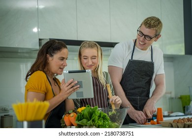 Family Cooking,Happy Family In The Kitchen Having Fun And Cooking Together,Using Digital Tablet For Checking Vegetable Salad Recipe Online.

