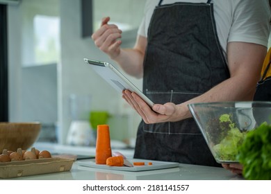 Family Cooking,Happy Family In The Kitchen Having Fun And Cooking Together,Using Digital Tablet For Checking Vegetable Salad Recipe Online.

