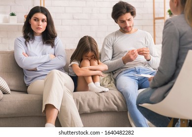 Family Counselling Concept. Unhappy Man And Woman And Their Upset Little Daughter Sitting At Psychologist's Office, Having Therapy