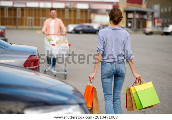 Family couple\
with bags in cart on car\
parking