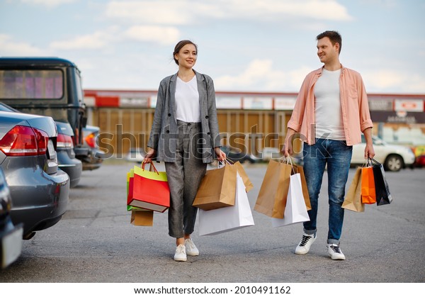 Family couple\
with bags on supermarket\
parking