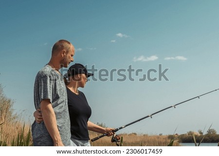 Family couple fishing together on the river bank. Enjoying calm and relax of nature