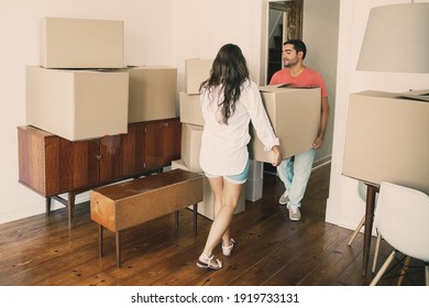 Family couple leaving their apartment, carrying carton boxes and furniture. Full length. Moving or relocation concept