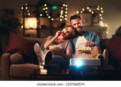 Family couple watching television projector at home on the sofa