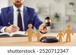 In family court, a lawyer delivers a verdict on divorce proceedings, wielding a gavel, beside wooden family figurines, symbolizing legal judgement regarding custody, children, and justice.