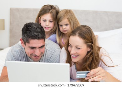 Family With Credit Card Shopping Online In Bedroom