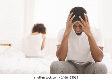 Family Crisis. Desperate African Man Sitting On Bed And Thinking, His Girlfriend On Background, Empty Space